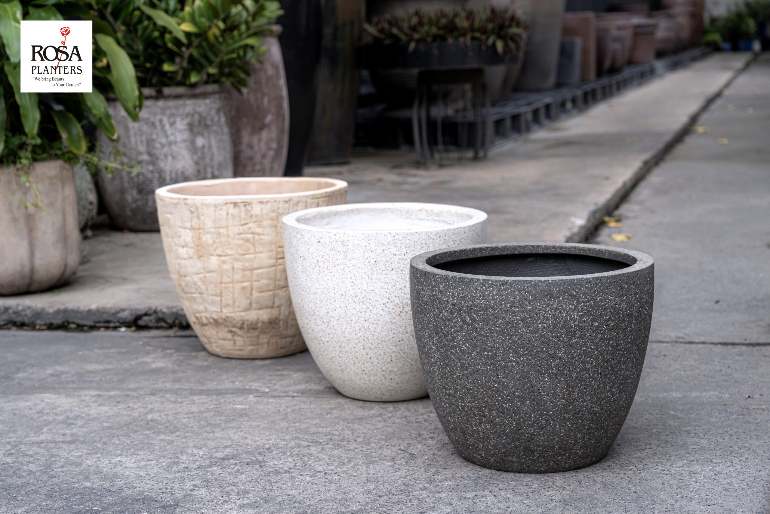 Comparison of polystone, fiber concrete, and ceramic plant pots of the same shape side by side