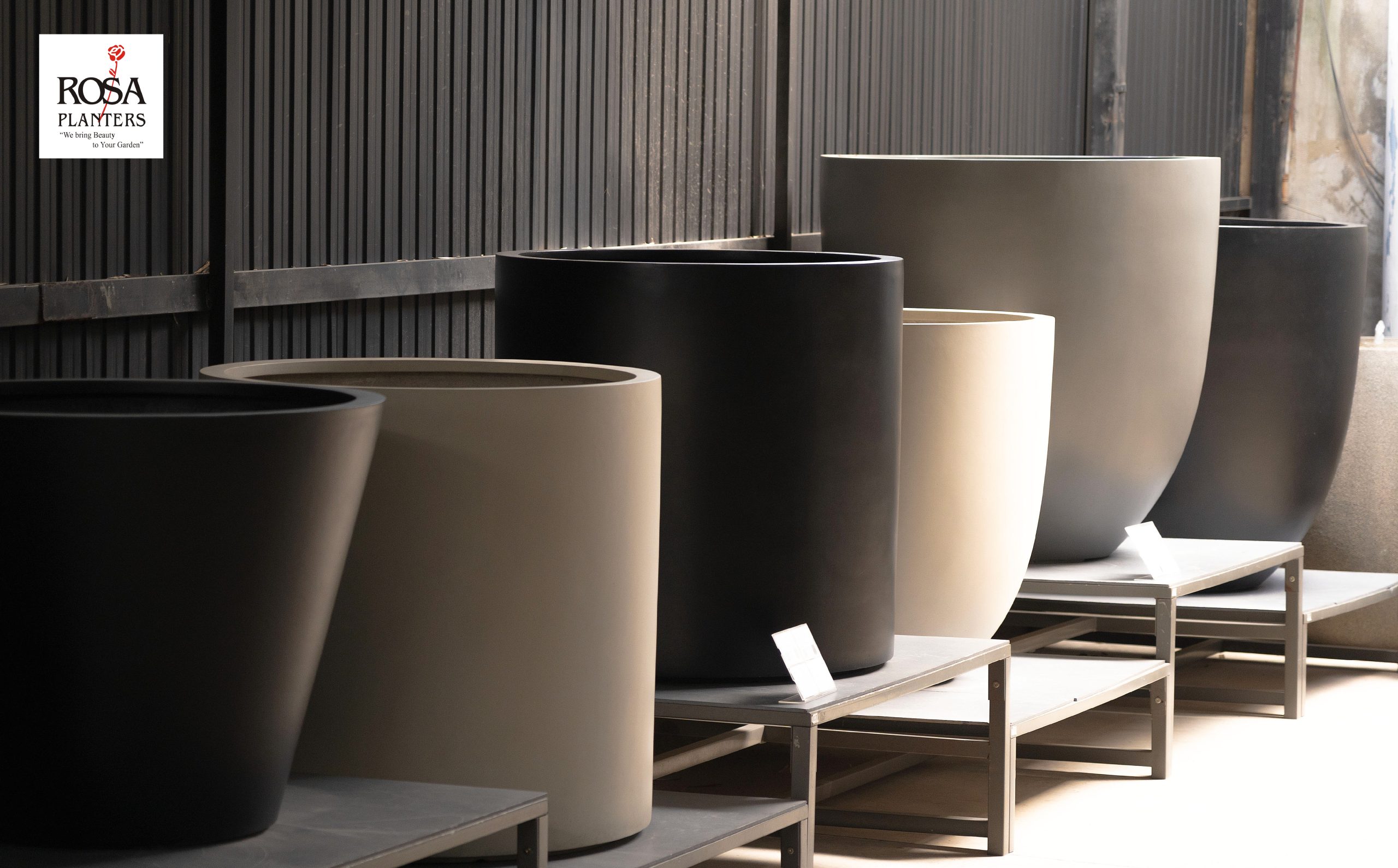 Large polystone planters on display shelves in a showroom